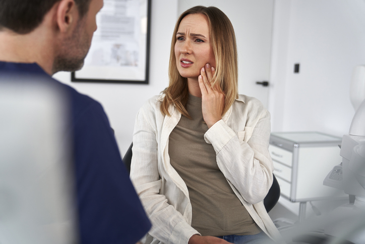 Patient holding her cheek in pain while speaking with a dentist at Dental Matters